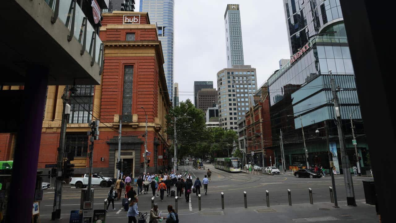 An urban intersection in Melbourne with skyscrapers and pedestrians.