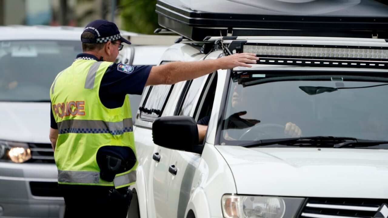 A Queensland police officer gestures for a motorist to pull over at a checkpoint at Coolangatta on the Queensland-New South Wales border, Friday, May 22, 2020