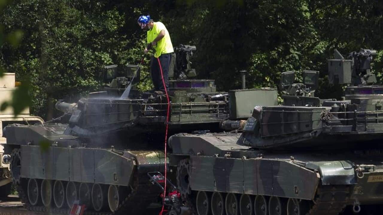 A worker washing an Abrams tank, for July 4 celebrations