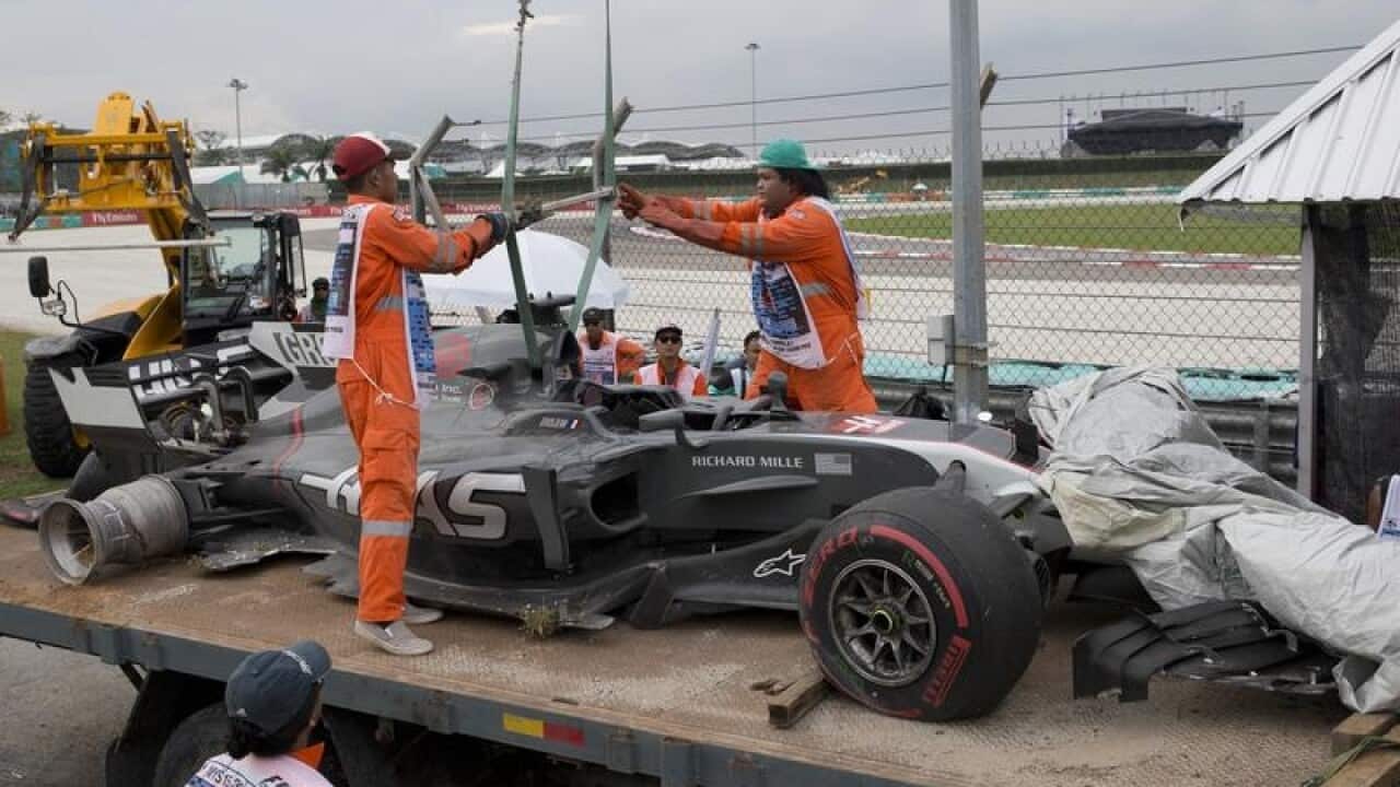 Track crew lifts the car of Haas driver Romain Grosjean