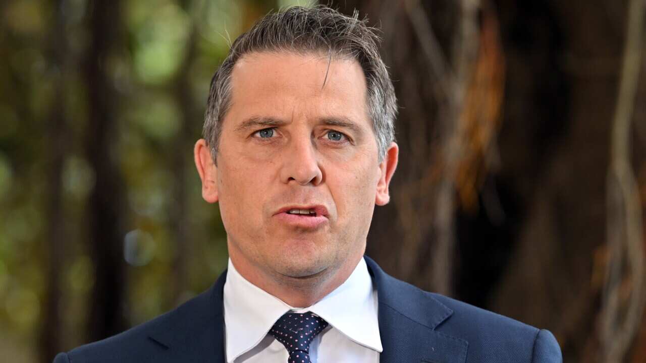 A man in a blue suit and tie speaking to the media
