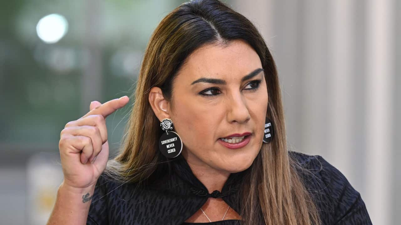 lidia thorpe gestures pointedly, wearing a black top and black earrings bearing the words "Sovereignty never ceded"