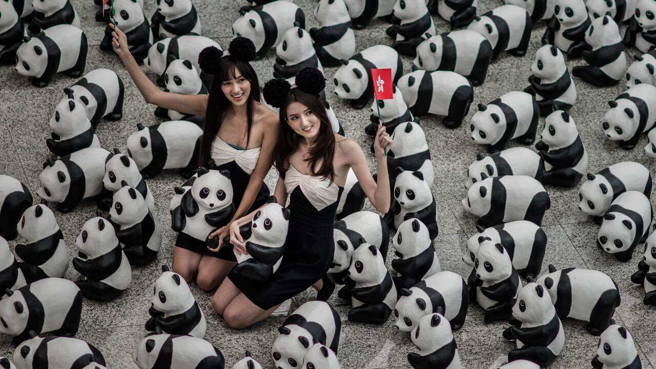 Models pose with some of the 1,600 papier-mache pandas displayed at Hong Kong's international airport on June 9, 2014. (AAP)