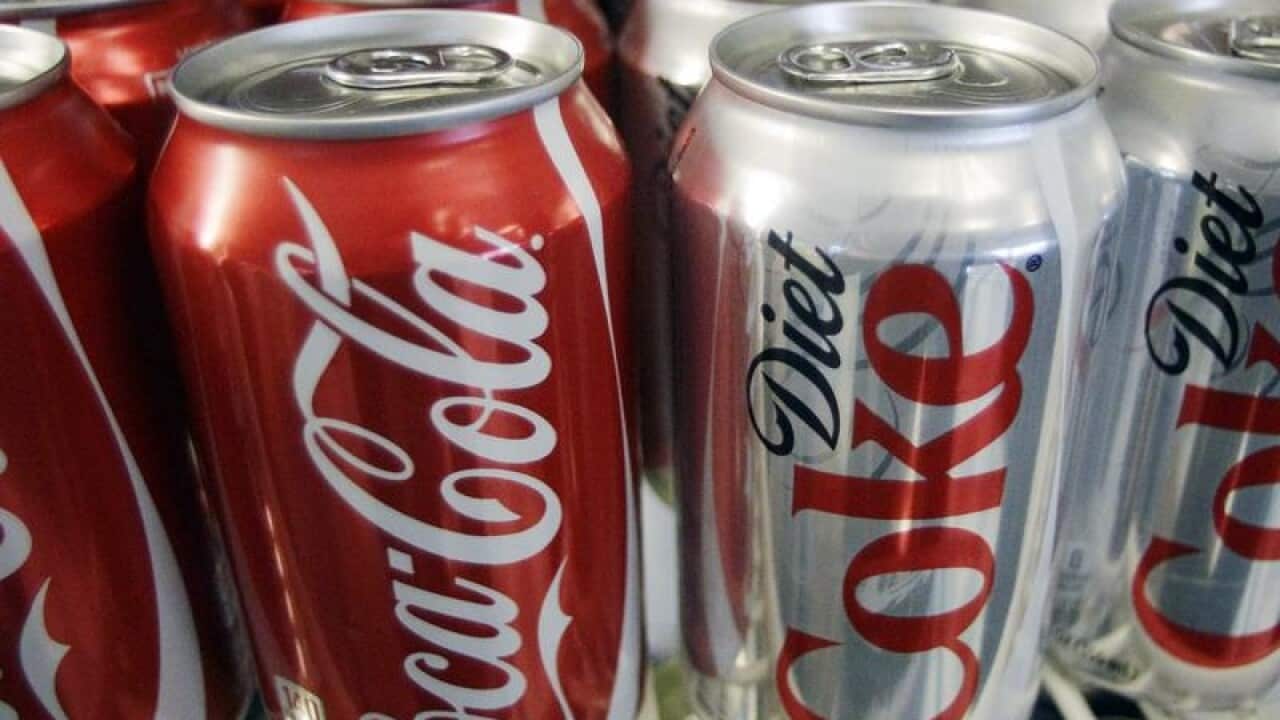 Cans of Coca-Cola and Diet Coke sit in a cooler