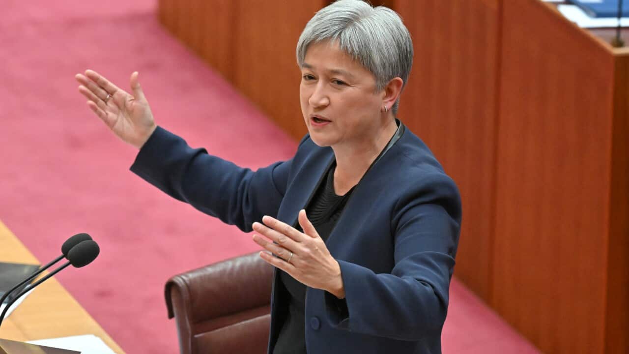 A defence personnel stands by a military vehicle on a deserted street while two others converse with a civilian nearby.