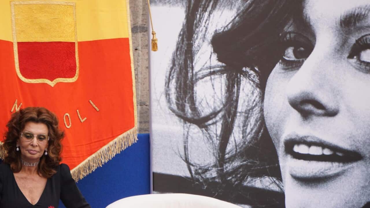Sophia Loren sits near a giant portrait of herself