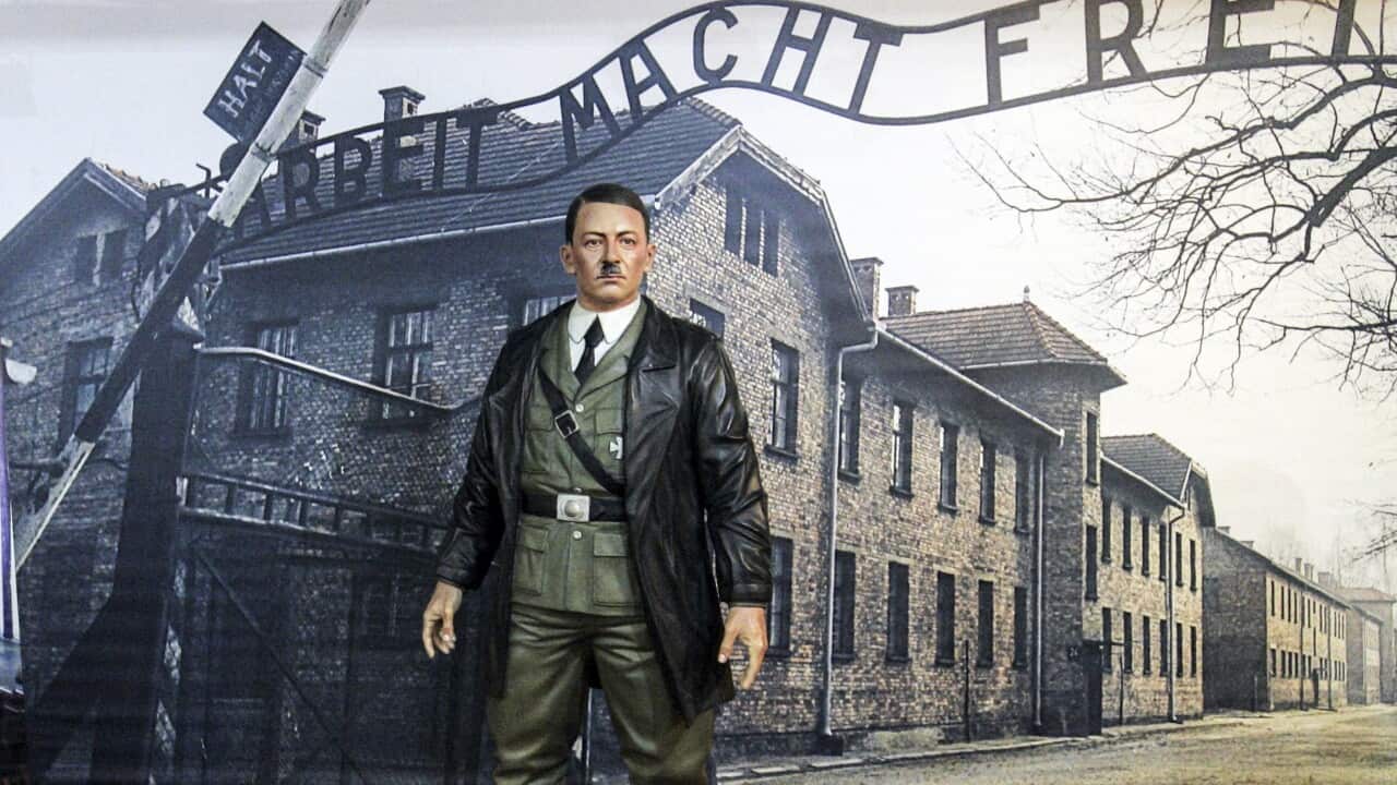 A wax statue of Adolf Hitler is displayed in front of a picture of the Auschwitz-Birkenau concentration camp at the Indonesian museum.
