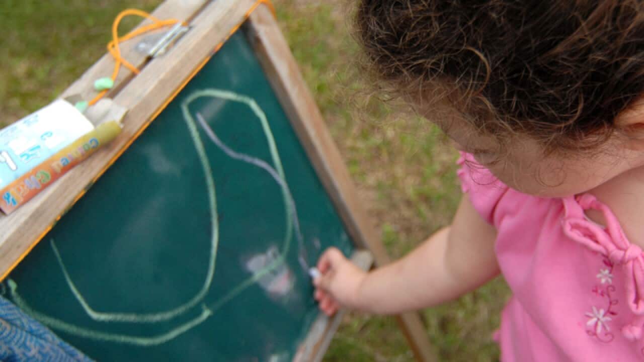 A stock image of a young girl drawing on a chalkboard