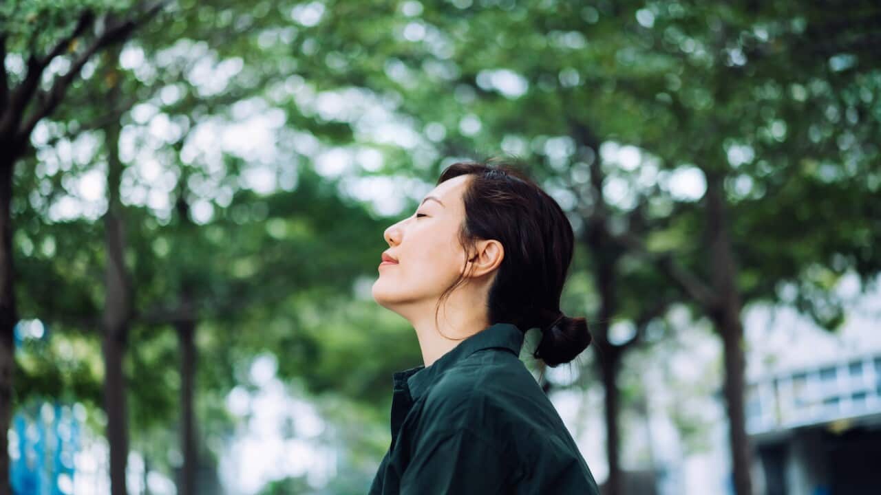 Young woman enjoying a gentle breeze with her eyes closed - Great Minds - Metta