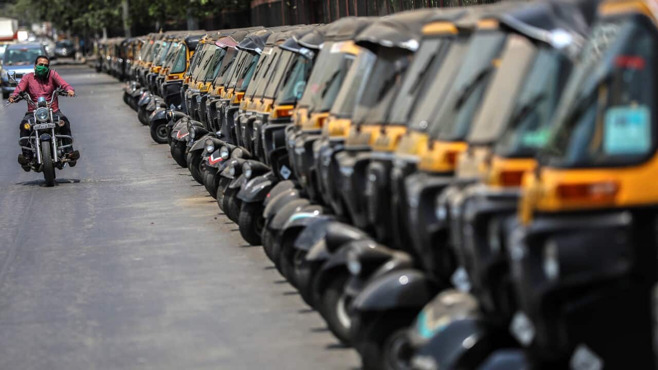 An Indian man on his bike passes the parked auto rickshaw during a nation wide lockdown in Mumbai, India, 15 May 2020.