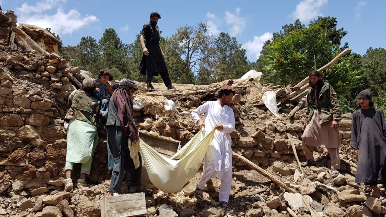 People carry a dead body removed from debris of a building after an earthquake shook Afghanistan