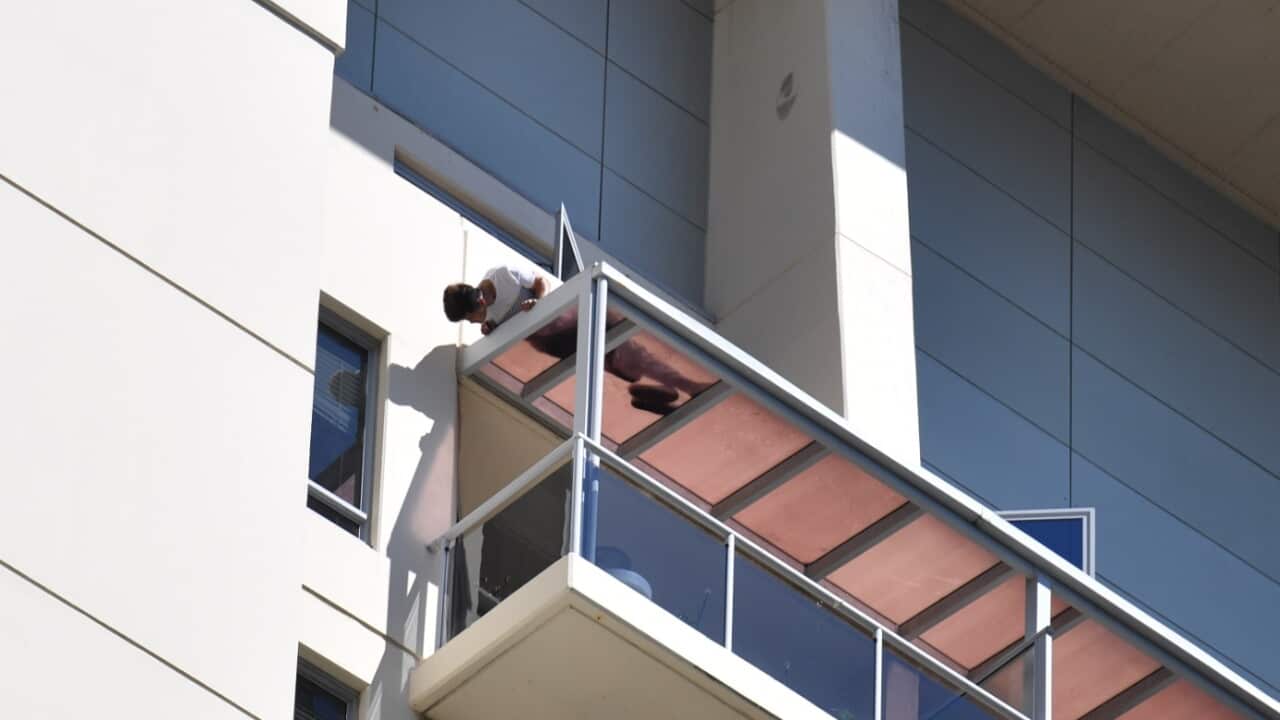 A man is seen on a ledge on an apartment building in Chatswood, Sydney, Monday, October 9, 2017.