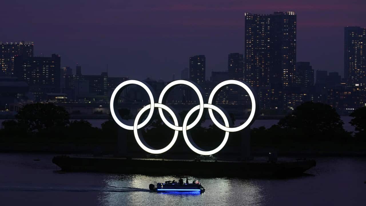 The Olympic rings float in the water at sunset in Tokyo.