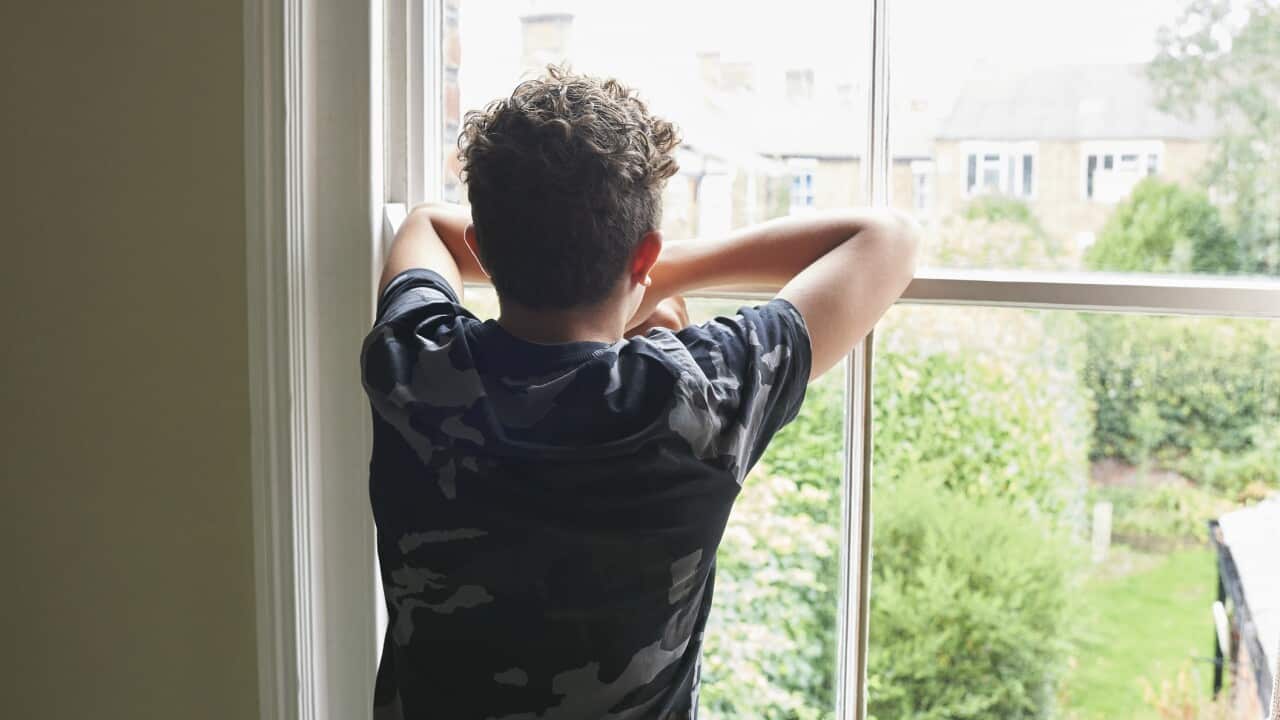 Teenage boy looking out of bedroom window