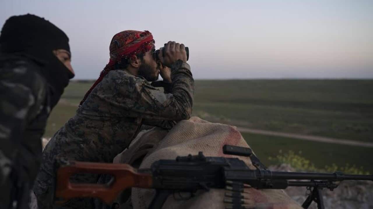 A file image of SDF fighters watching an airstrike on Baghouz