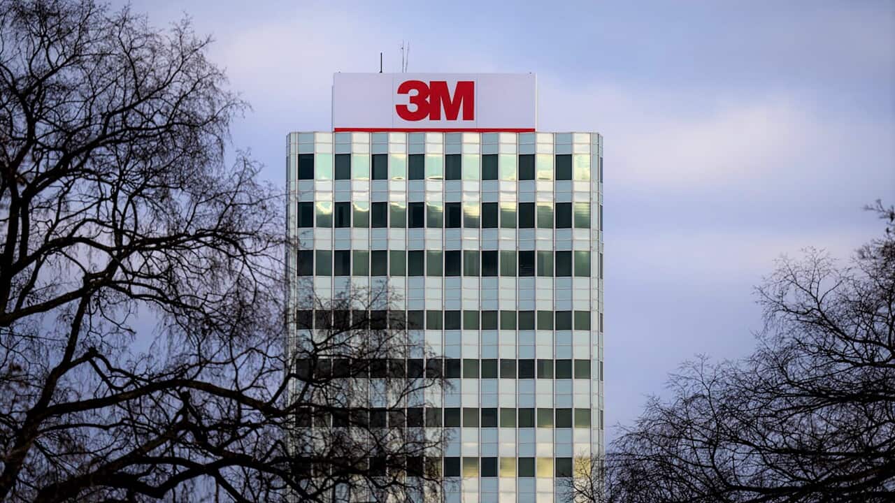 A tall office block with the 3M logo in red at the top stands behind trees.