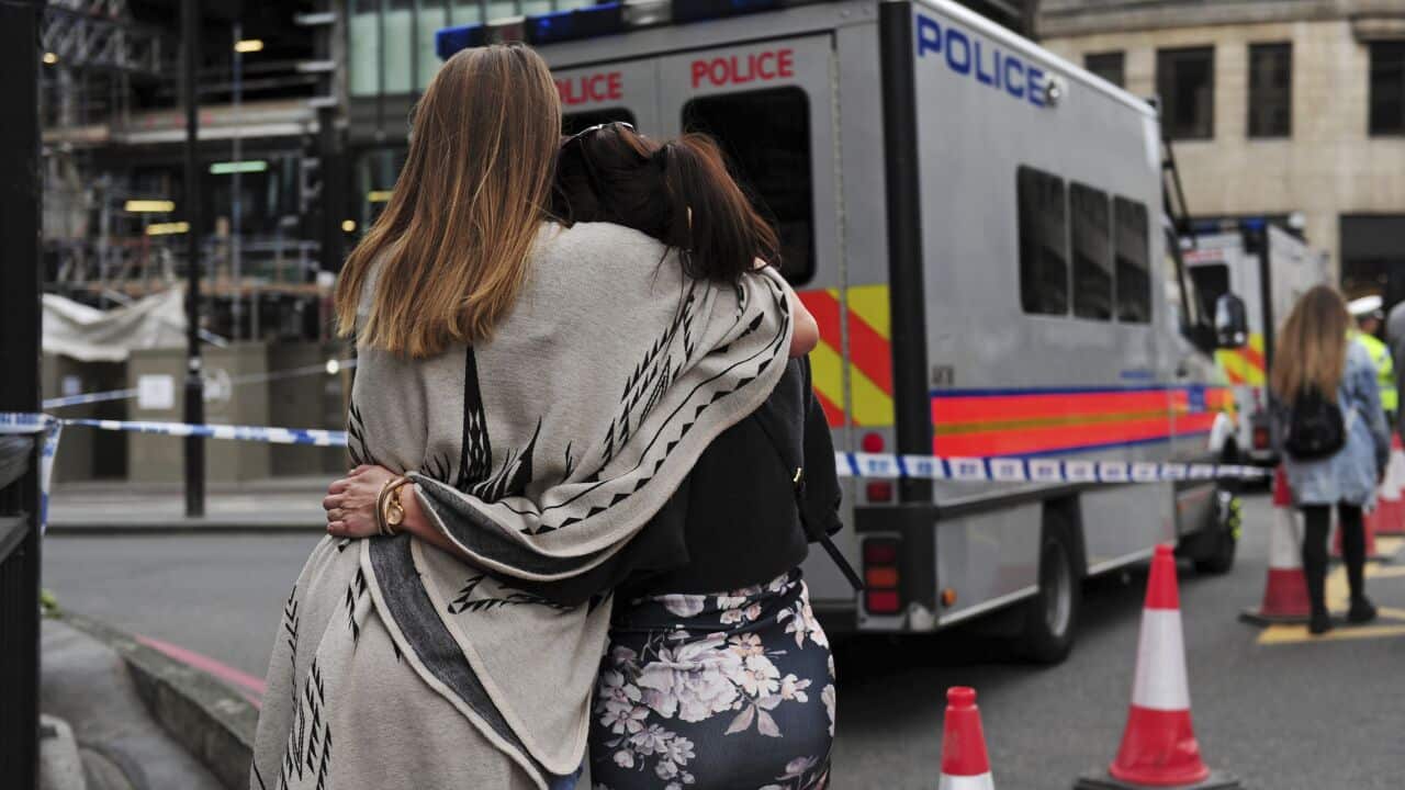 Two women hug after bringing flowers to add to tributes laid on the north side of London Bridge following last night's terrorist incident.