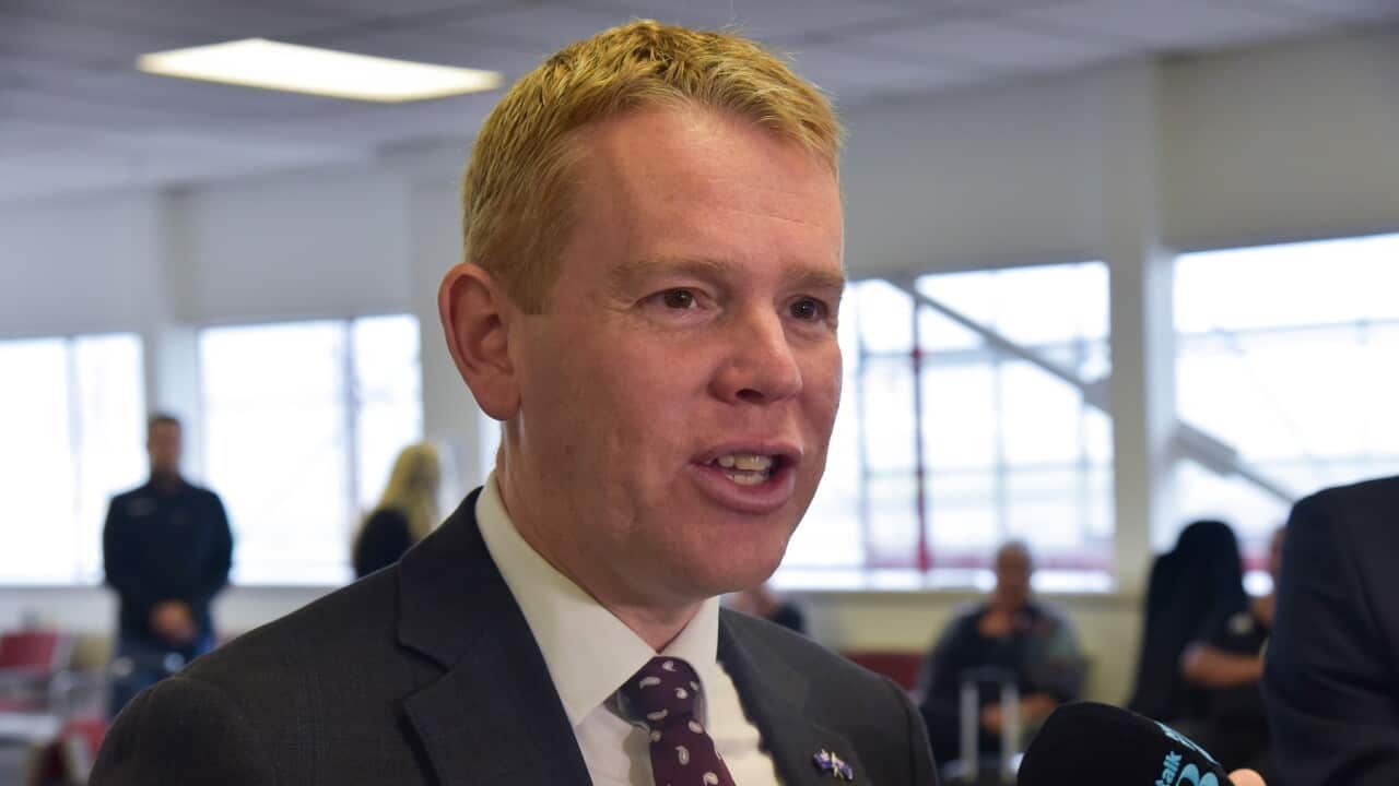 A man in a black suit, white shirt and red tie.