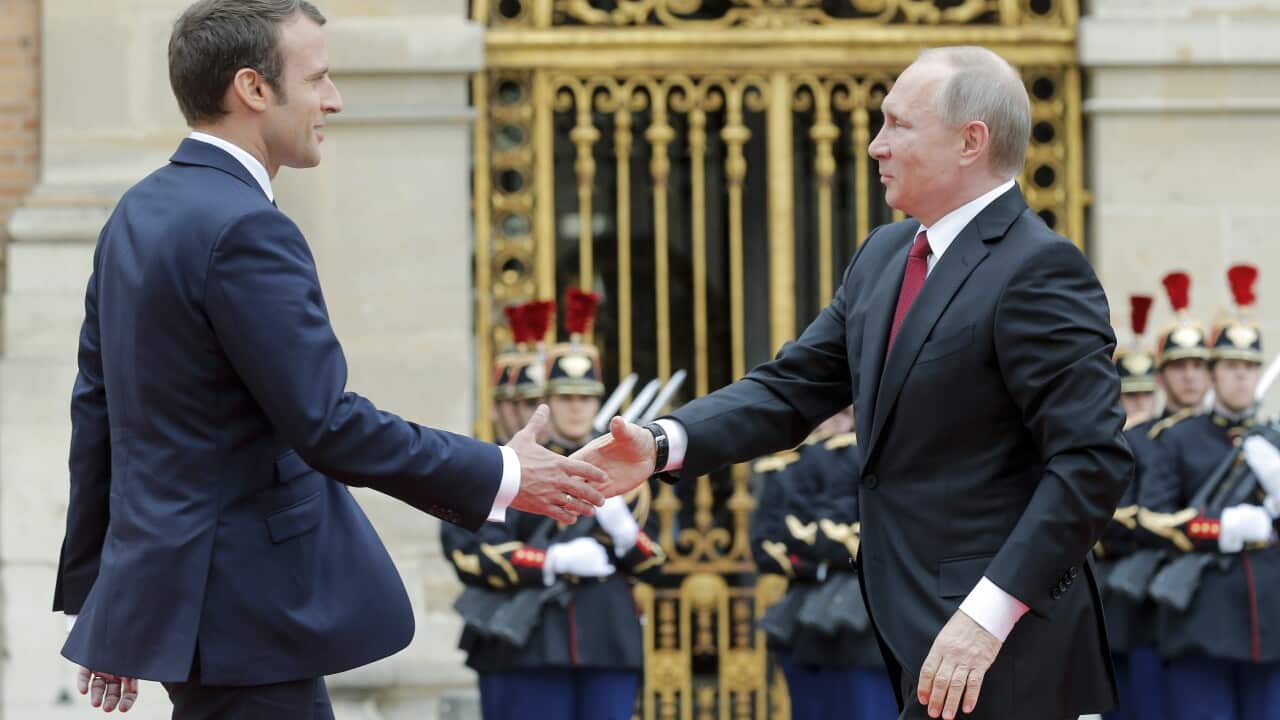 Russian President Vladimir Putin, right, is welcomed by French President Emmanuel Macron at the Palace of Versailles,