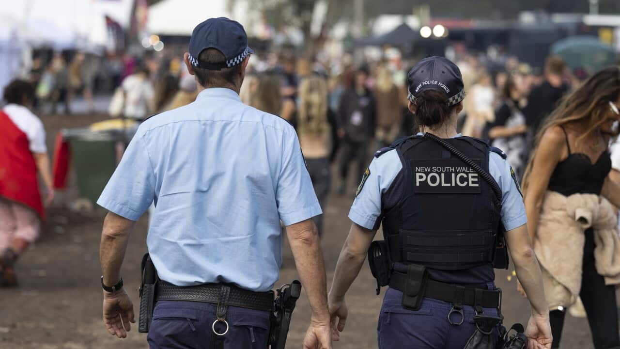 Two police officers in uniform walking through a music festival.