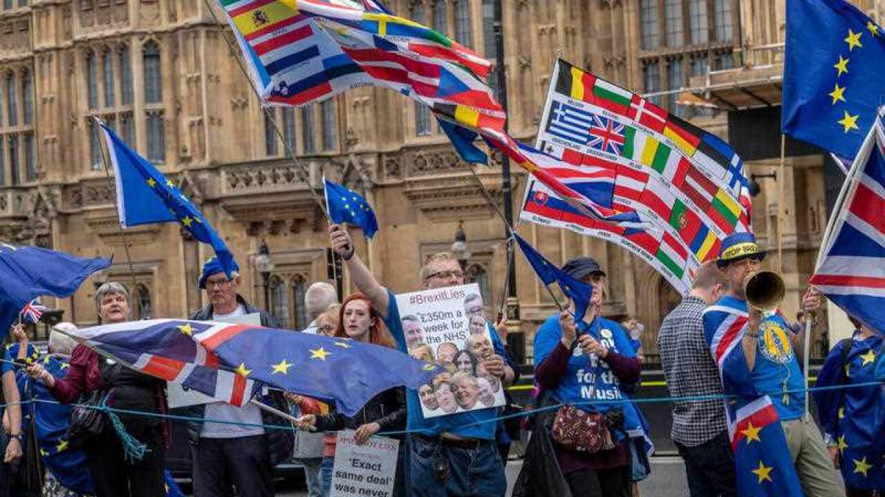 Anti-Brexit demonstrators wave flags as they rally outside of the House of Commons in London in June 2018.
