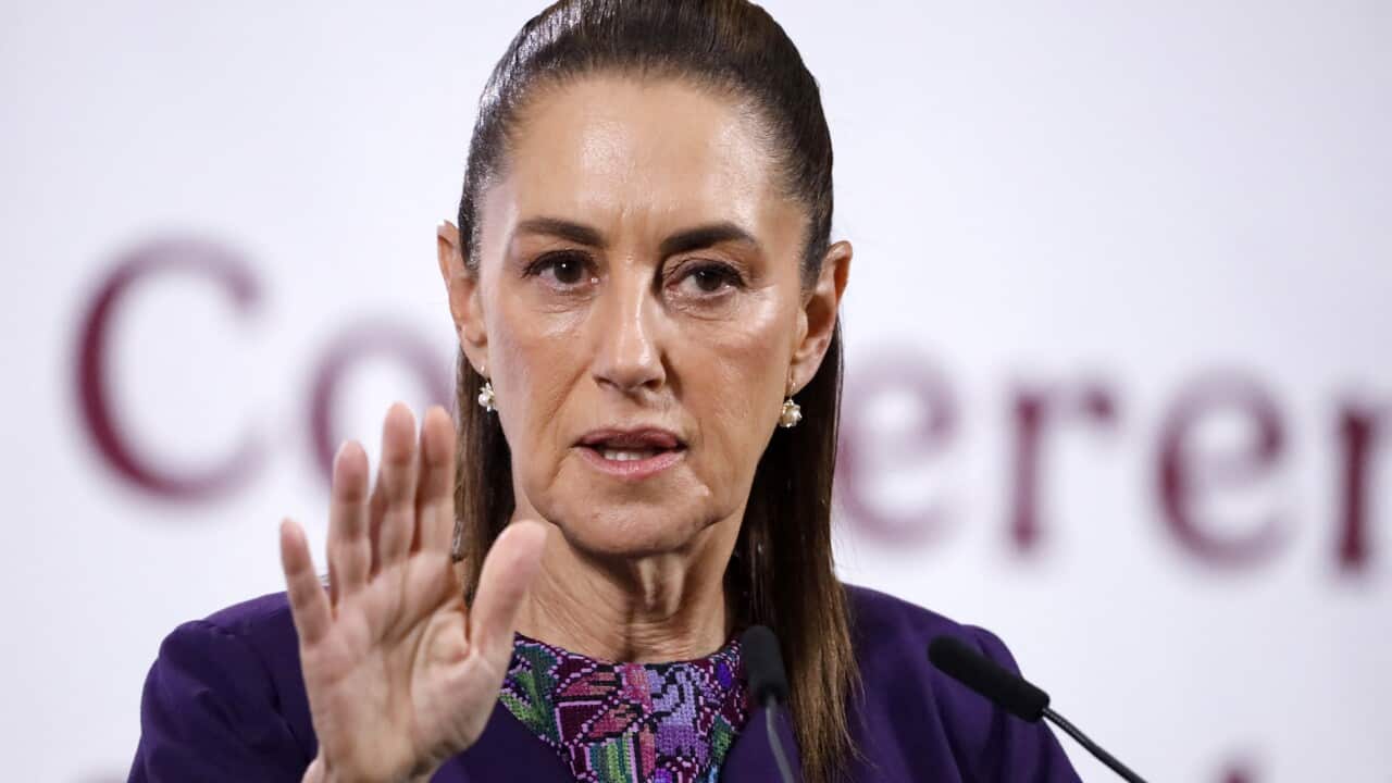 A woman at a press conference holding a hand up