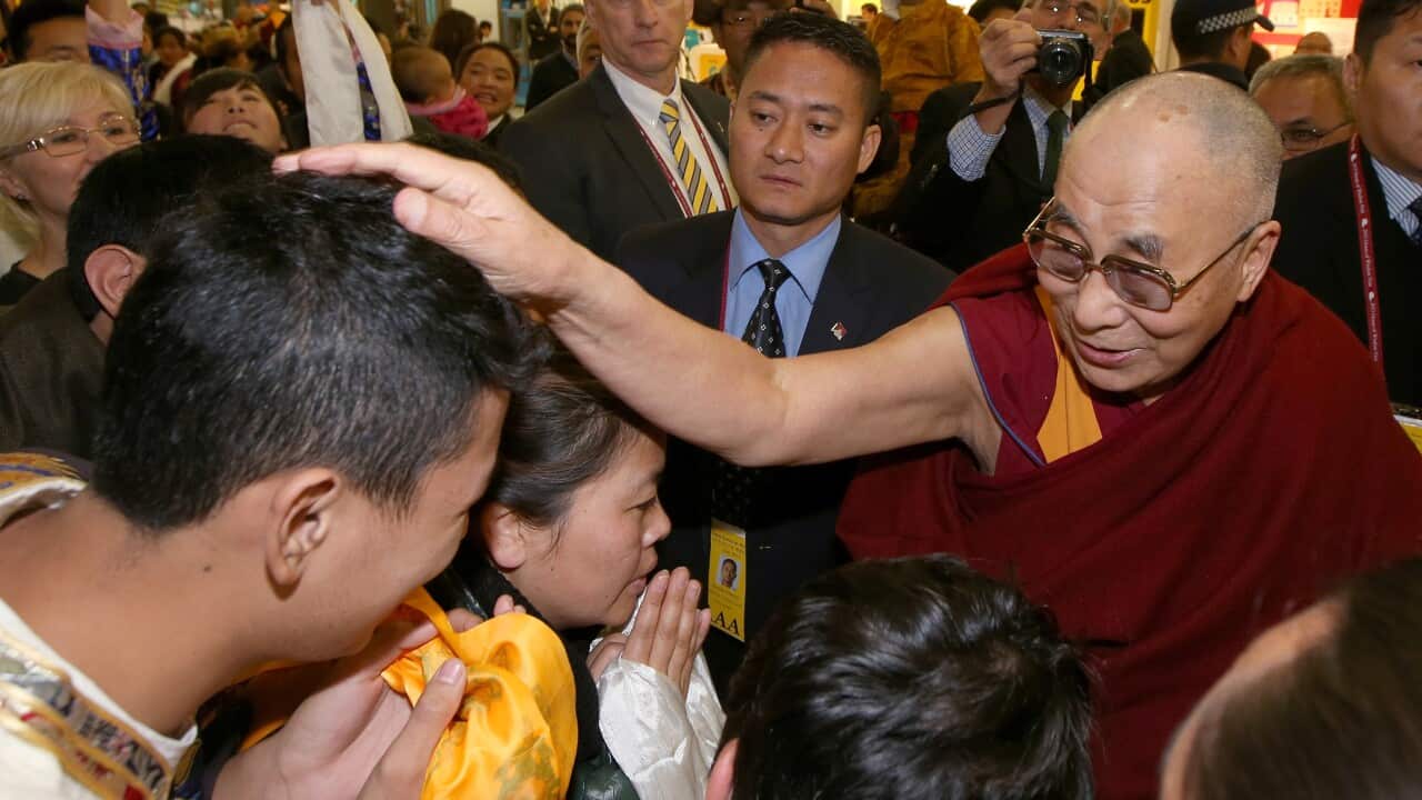 The Dalai Lama, right, places his hand on a man's head as he arrives in Sydney, Thursday, June 4, 2015. The Tibetan spiritual leader is visiting Australia for the 10th time. (AP Photo/Rick Rycroft)