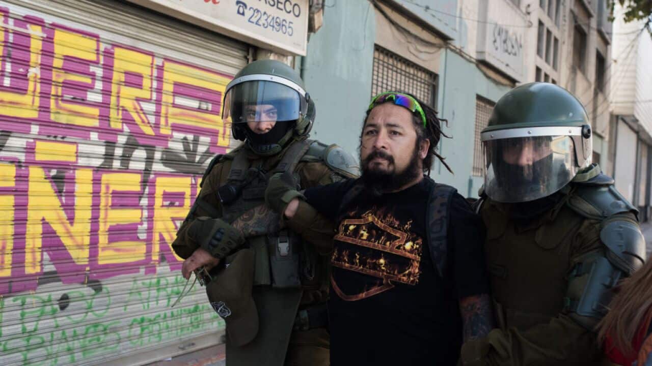 Security guards detain a demonstrator in Chile.