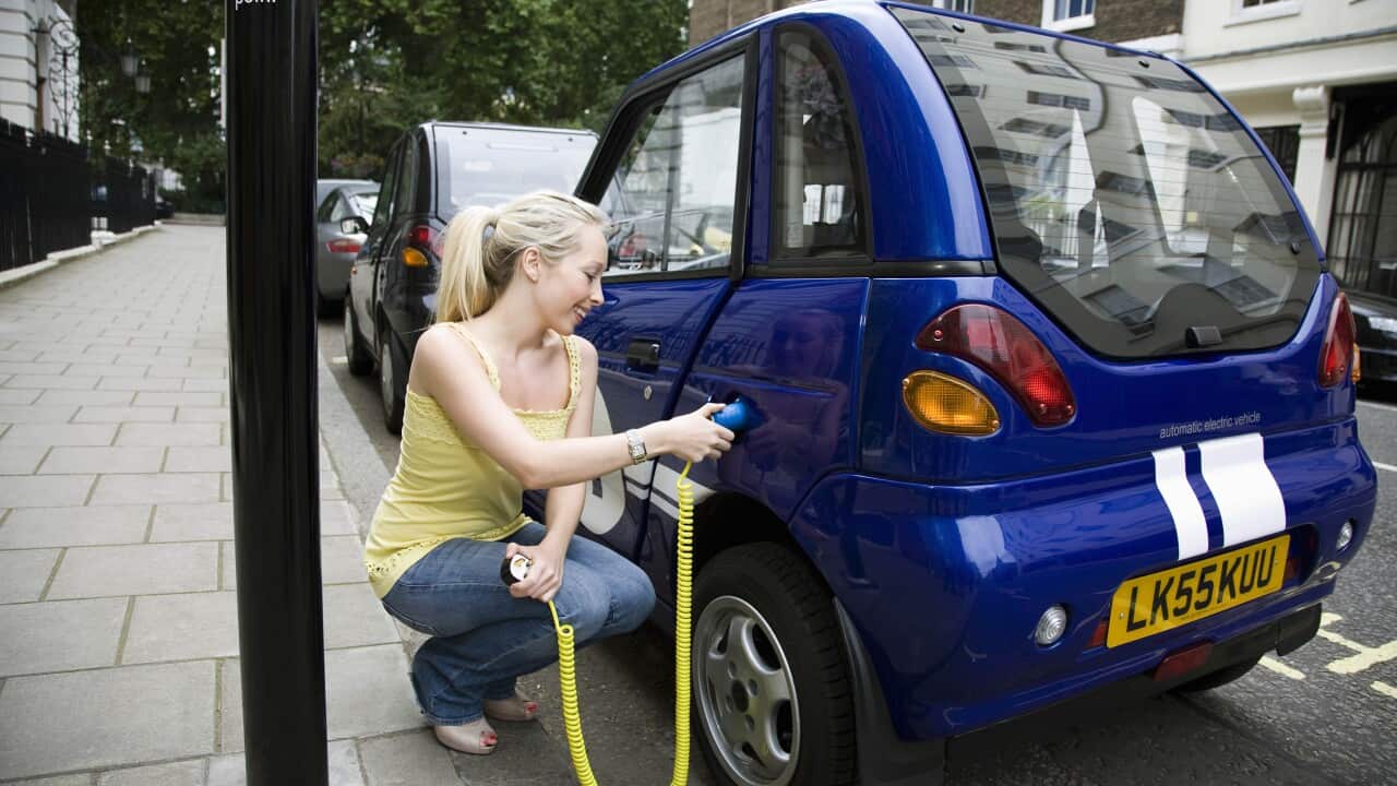 Young woman charging electric car
