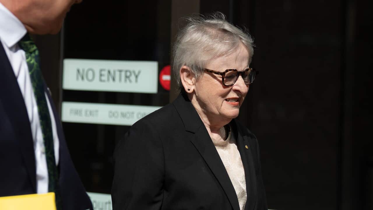 A woman with a black jacket and black glasses pictured outside a court