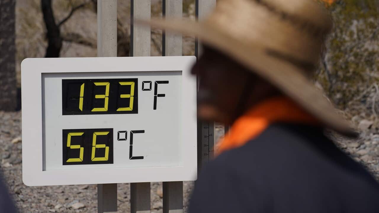 People visit a thermometer on July 11, 2021, in Death Valley National Park