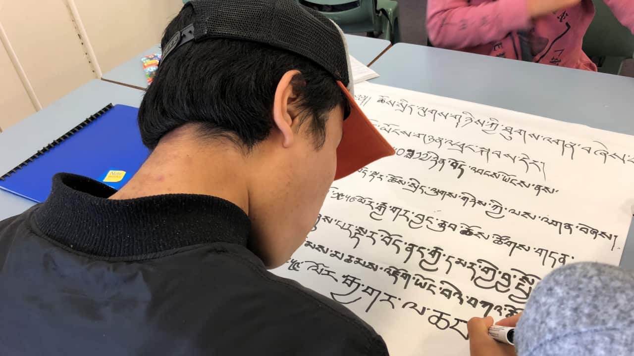 Tibetan boy writing Tibetan script