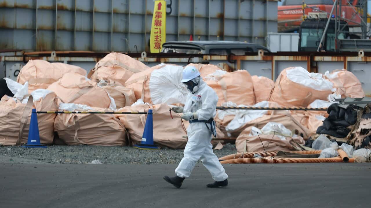 A worker walks past radioactive waste at Tokyo Electric Power Co.'s embattled Fukushima Daiichi nuclear power plant.