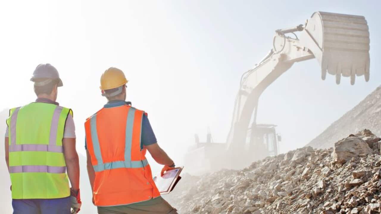 Workers watching digger in quarry