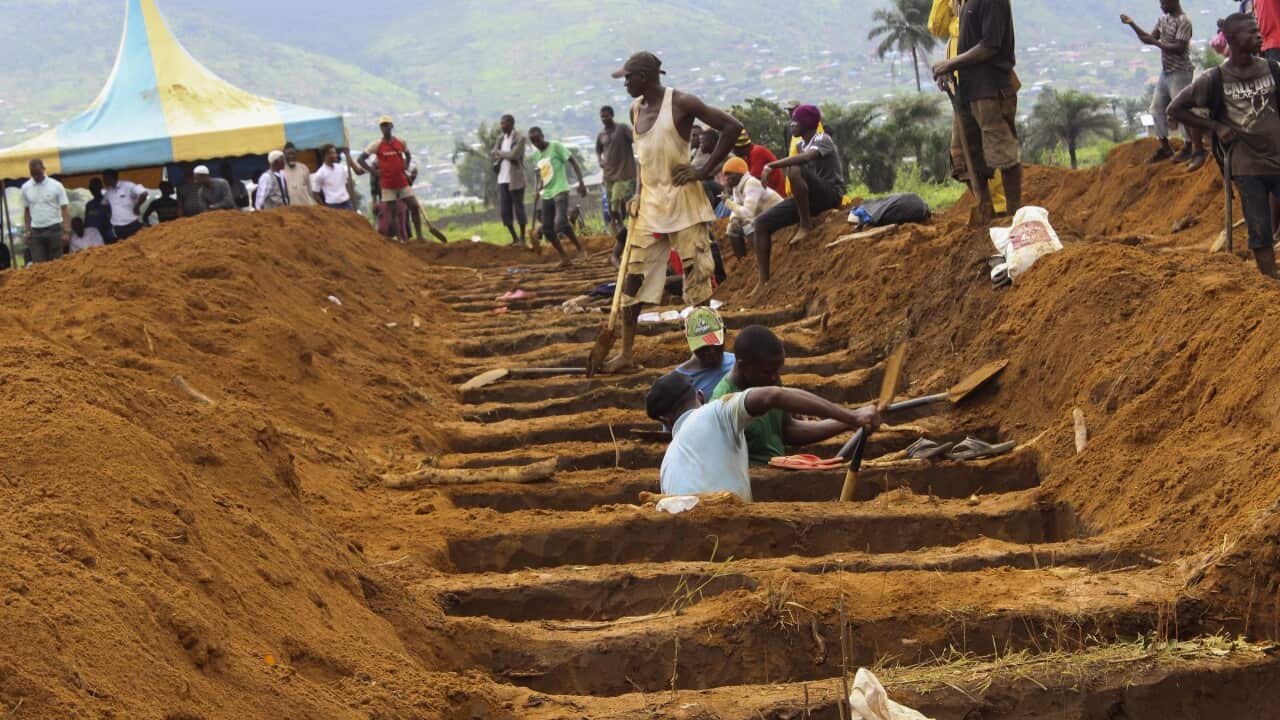 Workers dig mass graves for those who perished in a mudslide at a mass grave site in Waterloo, Sierra Leone.