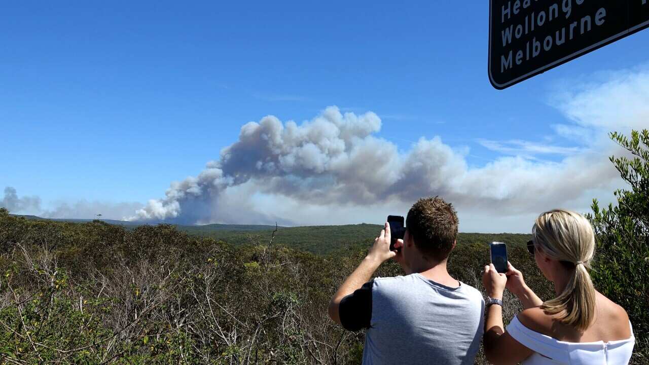 Onlookers take pictures as a fire burns in the Royal National Park.