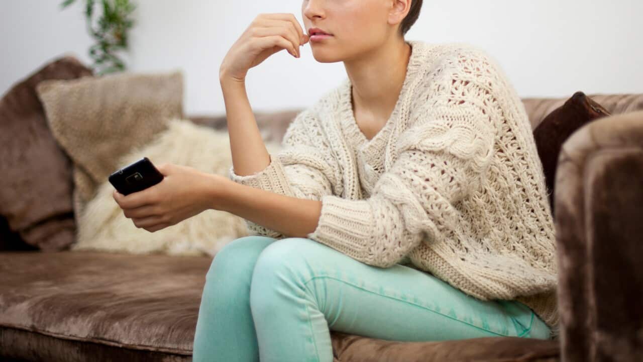 Young woman sitting on sofa with smartphone