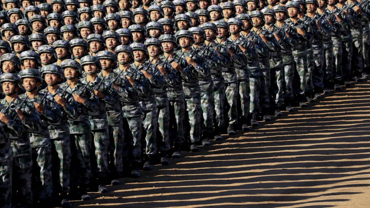 In this photo released by China's Xinhua News Agency, Chinese People's Liberation Army (PLA) troops march in formation Sunday, July 30, 2017