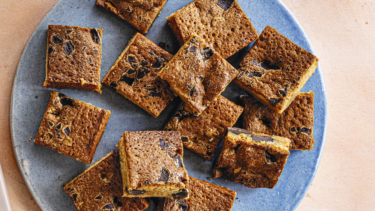 Blondie squares, studded with dark chocolate, sit on a blue plate.