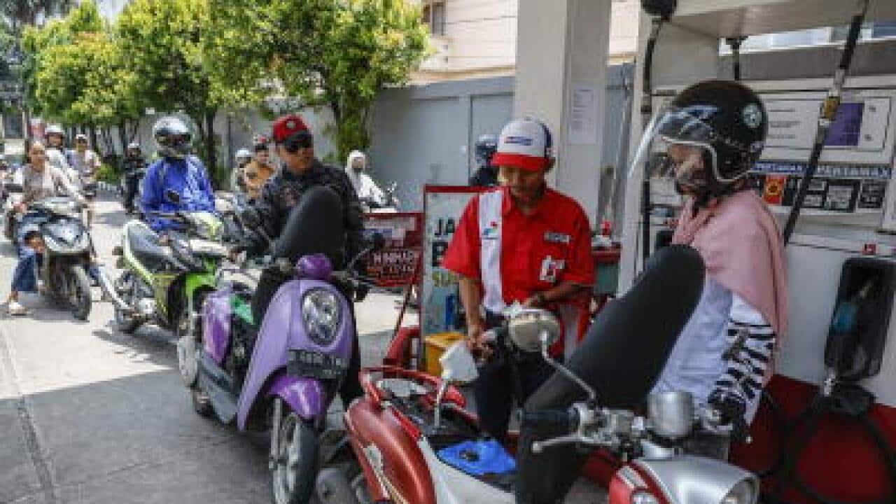 A worker refuels a motorbike at a gas station in Jakarta, Indonesia, while others waiting for their turn, 01 April 2026. EPA/MAST IRHAM.