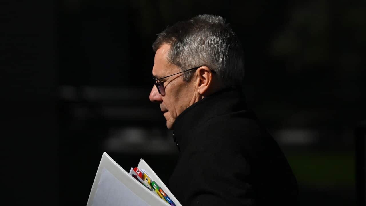 Shane Drumgold holding a folder of documents