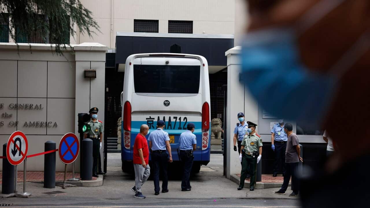 Chinese paramilitary policemen guard the gates as it opens to let a bus enter the United States Consulate in Chengdu.