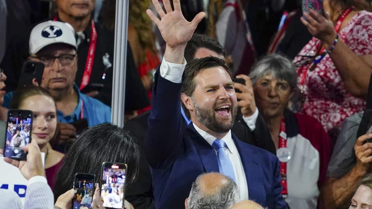 JD Vance smiling and surrounded by reporters.