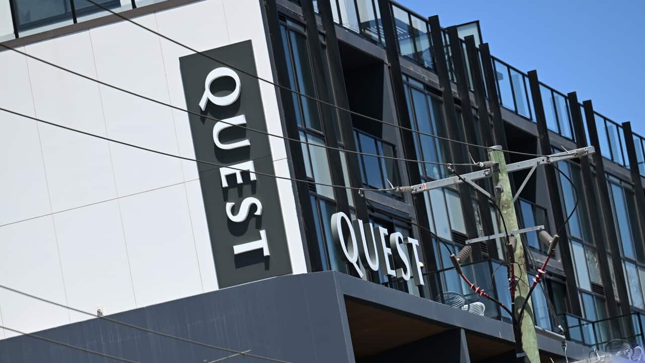 The side of a hotel building which has signs saying "Quest" on it.