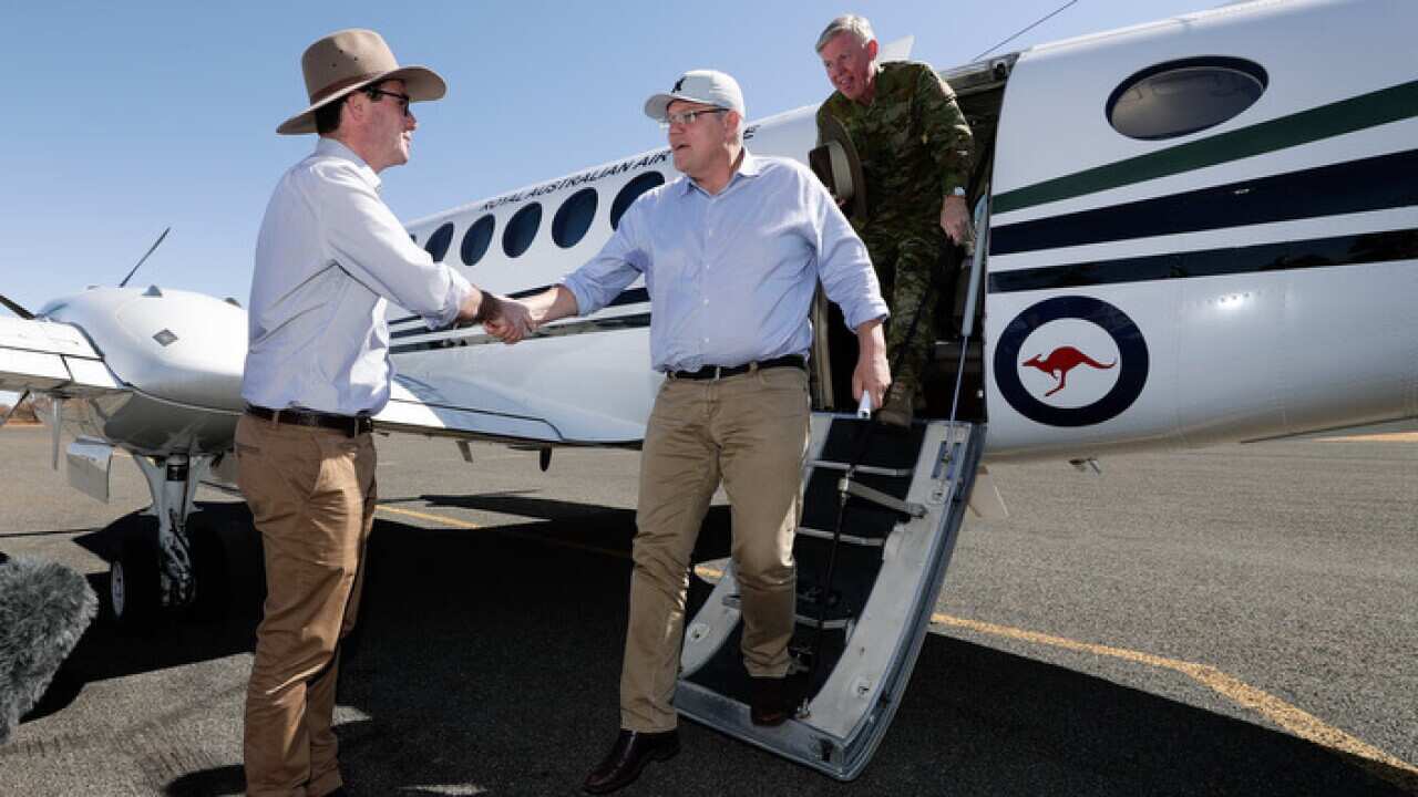 Prime Minister Scott Morrison (c) arrives at Quilpie Airport in southern Queensland
