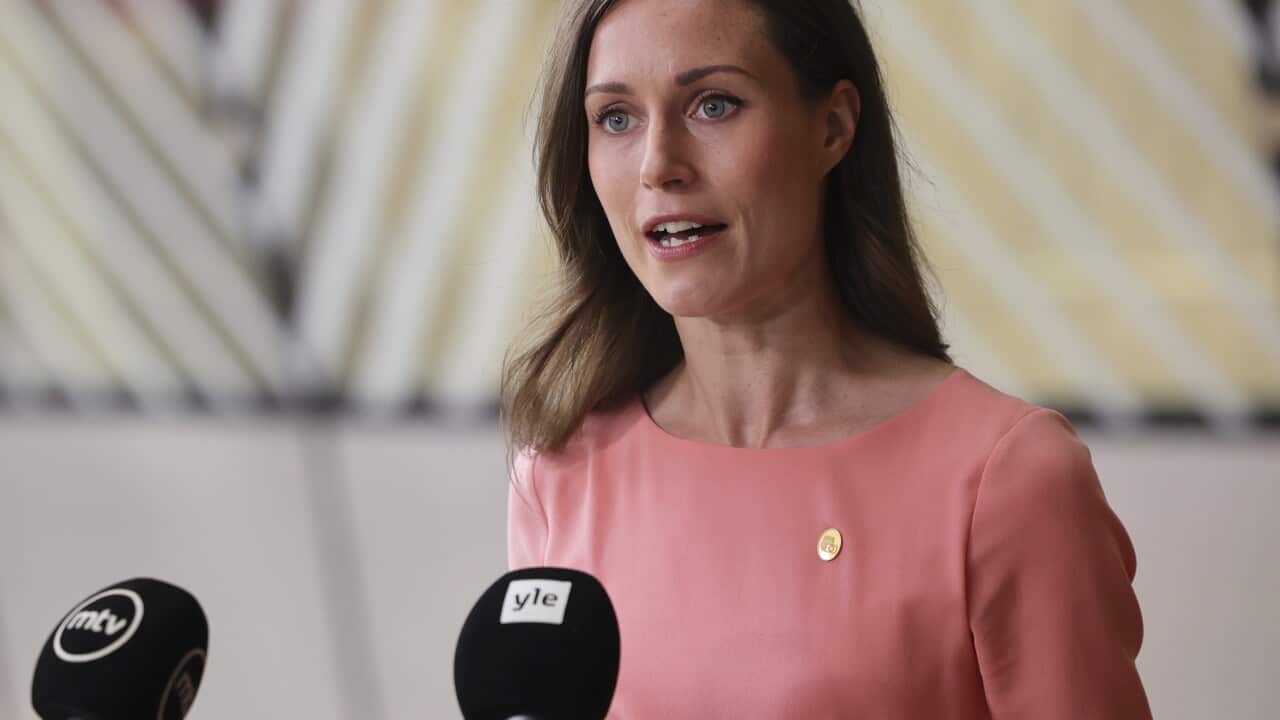 Finland's Prime Minister Sanna Marin standing while speaking into microphones.