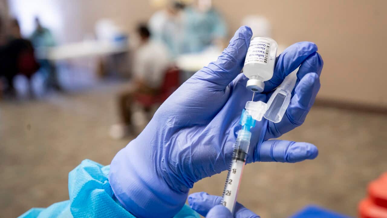 Gloved hands pull vaccine from a vial