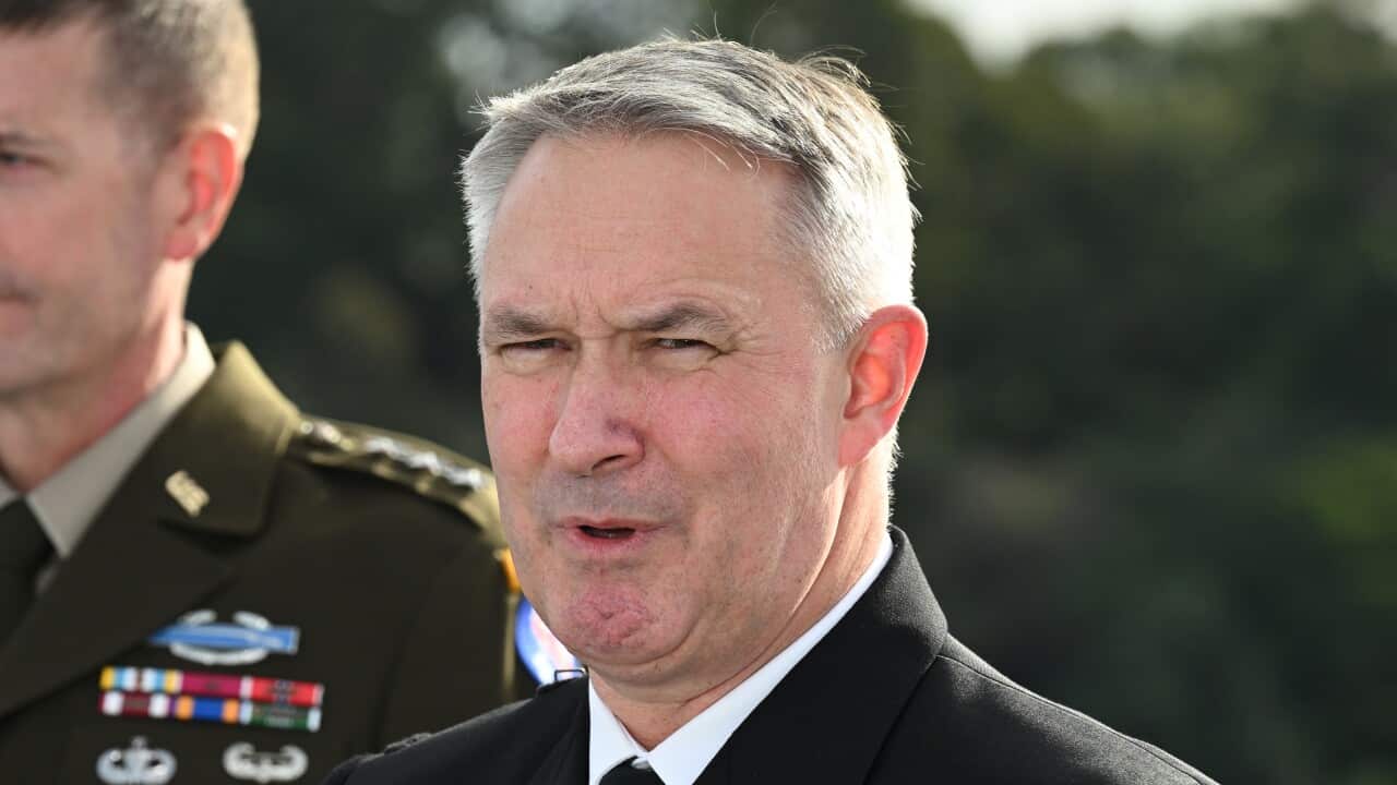 An Australian military official in uniform is speaking with another official standing at a distance on his right side.