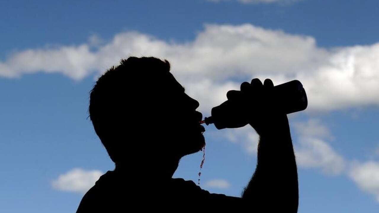 A file stock image of a silhouetted man drinking from a bottle.