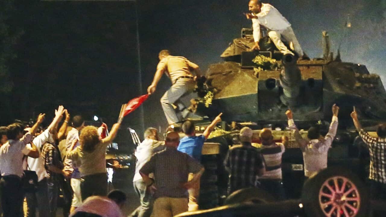 A tank moves into position as Turkish people attempt to stop them